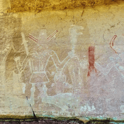 los Tres Reyes en el Sendero del mismo nombre. En esta foto pueden observarse no solo los elementos rituales de sacerdotes o chamanes, sino también el deterioro del color, que parece volver incompleto el diseño. La semejanza de las marcas de los petroglifos subyacentes sitúan estas representaciones en la época Clásica Fremont. Vernal, Utah