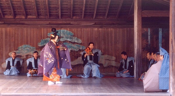 Hagoromo Apariencia del Shite como dama celestial. Obsérvese, a la derecha del pilar Metsukebashira, al Waki, sin máscara y con el vestido en sus manos.
