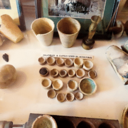 Instrumentos de laboratorio de ensayo (assay office) originales, utilizados para averiguar cuánto oro y plata contenía una muestra de mineral, una información decisiva para saber si una veta merecía ser explotada. Los recipientes grandes de la parte superior son crisoles (“crucibles”), en los que se calentaba mineral pulverizado mezclado con fundentes y compuestos de plomo; los pequeños recipientes alineados debajo son copelas (“cupels”), fabricadas tradicionalmente con un material muy poroso —frecuentemente ceniza de hueso— capaz de absorber el óxido de plomo durante la copelación. El oro y la plata quedaban finalmente concentrados en una diminuta perla metálica que podía pesarse y analizarse, decidiendo así si la veta merecía ser explotada o no. Estos instrumentos se encuentran en Bodie, un “pueblo fantasma” de la fiebre del oro de California, expuestos como curiosidad. Hoy en día, la mina de Bodie ha vuelto a funcionar, y se extrae oro mediante técnicas no tan diferentes de las de hace 200 años. (Haffty, Riley y Goss, 1977). (FA)
REFERENCIAS DEL APARTADO 06
• Haffty, J., Riley, L. B., y Goss, W. D. (1977). A manual on fire assaying and determination of the noble metals in geological materials (U.S. Geological Survey Bulletin 1445). U.S. Government Printing Office. https://digital.library.unt.edu/ark:/67531/metadc1115061/